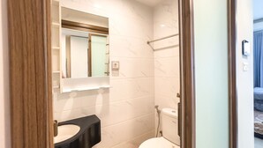 Un bagno moderno con un water bianco, un lavabo nero e uno specchio sopra il lavabo.