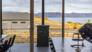 Un interior moderno con ventanas amplias que ofrecen vistas a un lago y montañas.