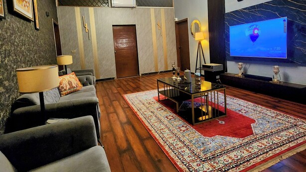 A living room with a sofa, a coffee table, a TV, and a patterned rug.
