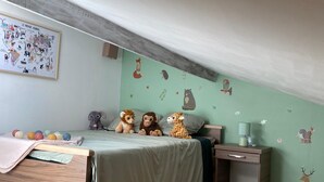 Ein Schlafzimmer mit einem Schlafpodest, einem kleinen Schreibtisch und einer Wand mit Tierstickern.