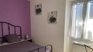 Ein Schlafzimmer mit Bett, Nachttisch, Heizkörper und zwei Wandbildern.