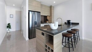 Een moderne keuken met een vast eiland, roestvrijstalen apparatuur en barkrukken.