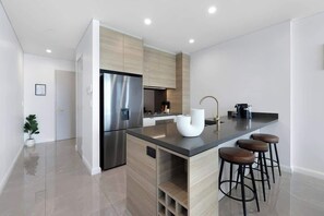 A modern kitchen with a built-in island, stainless steel appliances, and bar stools.