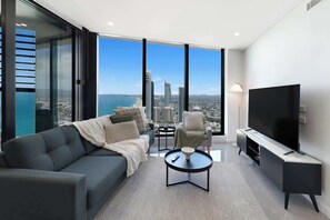 A modern living room with a city view, a sofa, a coffee table, a TV, and a chair.