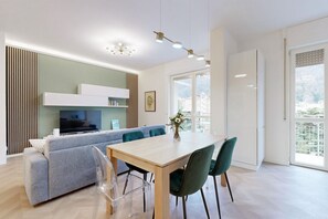 A modern living room with a sofa, dining table, chairs, and a TV.