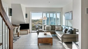 Ett modernt vardagsrum med en soffa, ett soffbord, en tv och en balkong med utsikt.