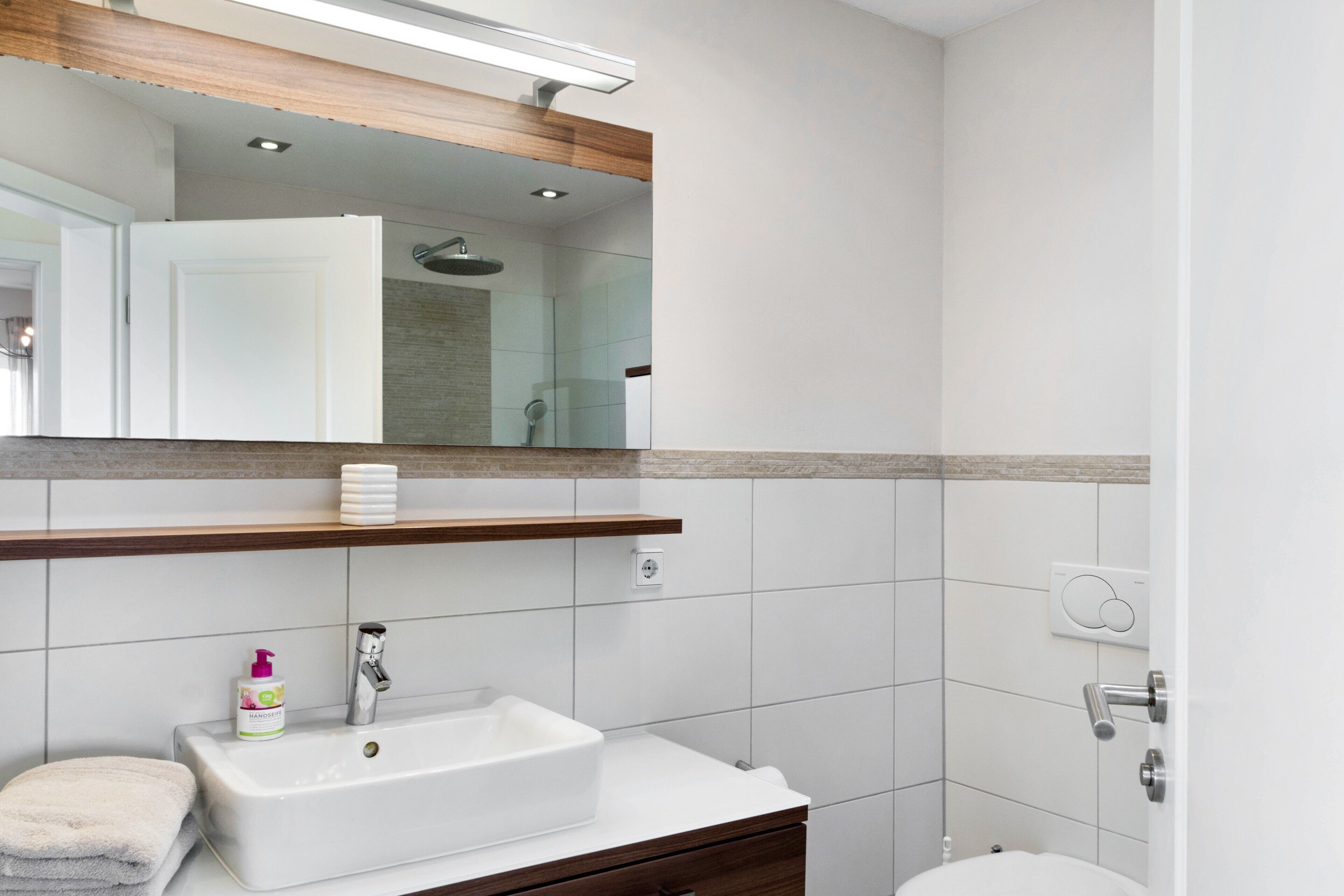 Une salle de bain avec un lavabo blanc, un miroir et une douche.
