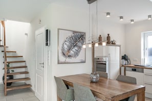 A modern kitchen with a wooden dining table, grey chairs, and a large feather artwork on the wall. - Esclusivo appartamento 5 * con vista sul mare (Borkum)
