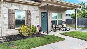 A two-story house with a stone facade, a green door, and a covered porch with outdoor seating. - Homestead - Close to Main St & 290 Wine Trail (Fredericksburg)