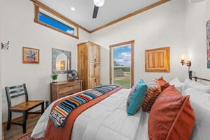 Quarto com cama, móveis de madeira, janela e ventoinha no teto.