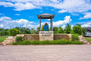 A sign for Arch Ray RV Resort with a gazebo structure, surrounded by greenery and a clear sky. - Rancho Relaxo - On the 290 Wine Trail (Fredericksburg)