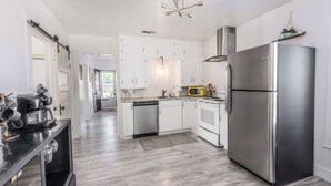 A modern kitchen with white cabinets, stainless steel appliances, and a wooden floor.
