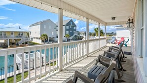 A covered outdoor area with a pool, white railings, and several lounge chairs. - 10% off 3-7 nights thru Oct. Pet friendly 4BR 2BA on channel. Fenced yard (North Myrtle Beach)