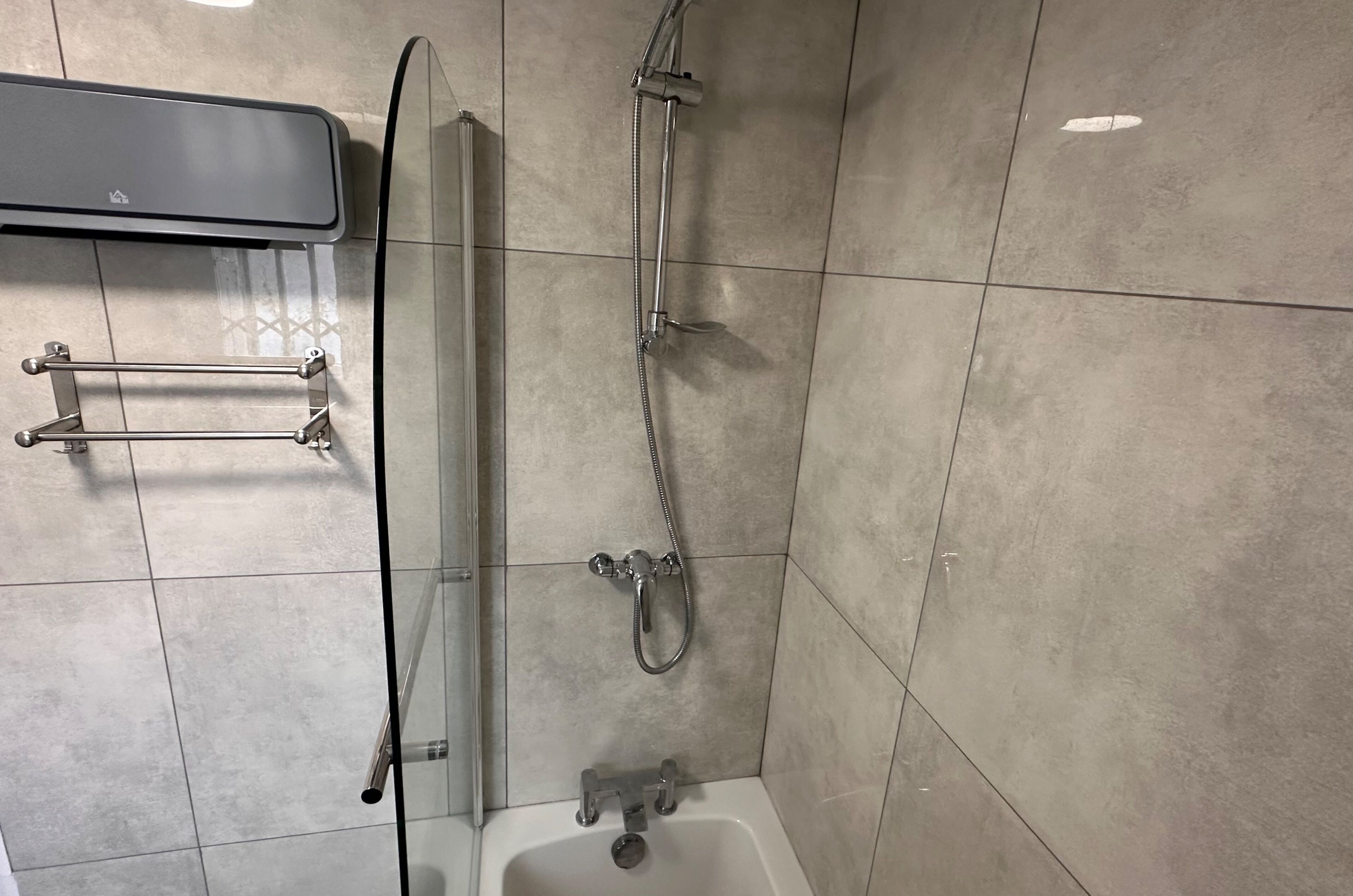 Un baño con cabina de ducha de vidrio, bañera y perchero para toallas.
