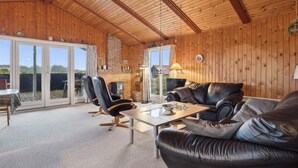 A cozy living room with a fireplace, leather sofas, and a dining table.