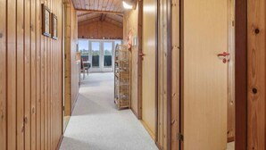 A wooden hallway with a carpeted floor, a wicker basket, and a door with a red handle.