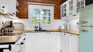 A modern kitchen with white cabinets, a wooden ceiling, and a window providing natural light. - 5 Star Holiday Home in Saeby (Sæby)