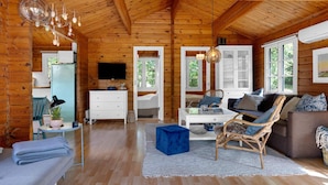 A cozy cabin interior with a wooden ceiling, a television, a dining area, and a seating area with a sofa and chairs. - 5 Star Holiday Home in Saeby (Sæby)