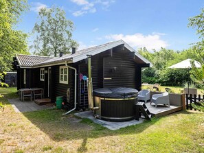 Une cabane en bois dotée d’un bain à remous, d’un espace salon extérieur et d’une petite terrasse.