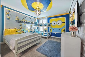 Ein Kinderzimmer mit Etagenbett, Minion-Dekoration und Deckenventilator.