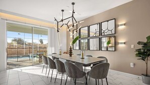 A spacious dining area with a large table, six chairs, and a modern chandelier. - Enchanting 7BR Disney  Villa Private Pool  Oasis (Davenport)