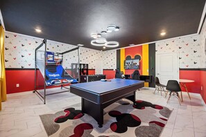 Ein Spielzimmer mit Billardtisch, Tischtennisplatte und Basketballkorb.