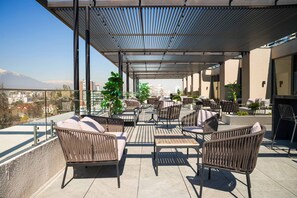 Une terrasse sur le toit avec des sièges extérieurs, une pergola et une vue sur la ville.