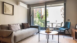 Ein modernes Wohnzimmer mit einem grauen Sofa, einem runden Couchtisch und einem blauen Sessel.