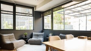 A modern interior with a wooden table, grey sofas, and large windows offering views of the outside. - Luxe 2BR Parkside Retreat | Pool and Gym Included (Providencia)