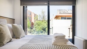 A hotel room with a bed, a view through a large window, and a radiator. - Luxe 2BR Parkside Retreat | Pool and Gym Included (Providencia)