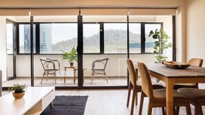 A modern dining area with a large table and chairs, a small side table, and a potted plant. - Chic 2BR Suite Vitacura | Steps From Everything (Las Condes)