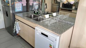A kitchen with a granite countertop, stainless steel sink, and a dishwasher. - Modern 4BR Apartment with Ocean View near Concón (Valparaíso)