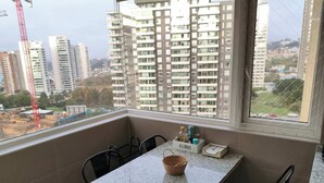 A balcony with a table, chairs, and a view of high-rise buildings. - Modern 4BR Apartment with Ocean View near Concón (Valparaíso)