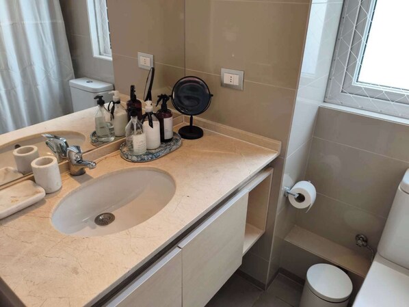 Un baño con lavabo, espejo, inodoro y ventana.