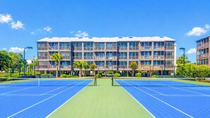 A tennis court with a building in the background.