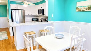 A kitchen with white cabinets, a stainless steel refrigerator, and a microwave.