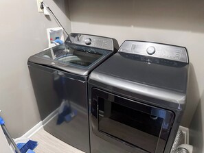 A compact laundry room with two front-loading washing machines and a dryer.