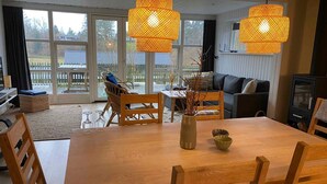 A cozy living room with a wooden dining table, chairs, a sofa, and a fireplace. - 5 Star Holiday Home in Ebeltoft (Ebeltoft)