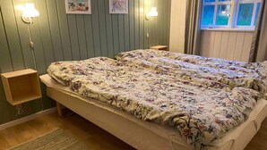 A double bed with floral bedding, two bedside tables, wall-mounted lamps, and framed pictures on a green paneled wall. - 5 Star Holiday Home in Ebeltoft (Ebeltoft)