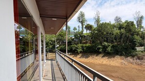 A covered balcony with a view of a dirt path and greenery. - Glass House Retreat (Valparai)