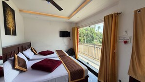 A hotel room with two beds, a ceiling fan, a TV, and a balcony with curtains. - Glass House Retreat (Valparai)