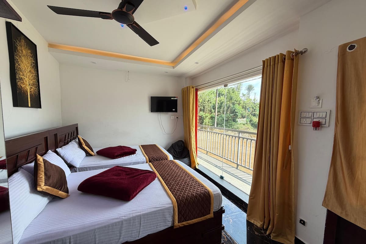 Une chambre d’hôtel avec deux lits, un ventilateur de plafond, une télévision et un balcon avec des rideaux.