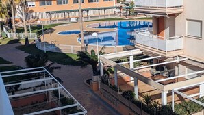 A hotel with multiple balconies, a swimming pool, and palm trees.