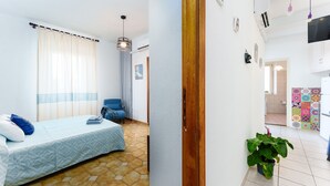 Een slaapkamer met een bed, een stoel, een potplant en een badkamer in de achtergrond.