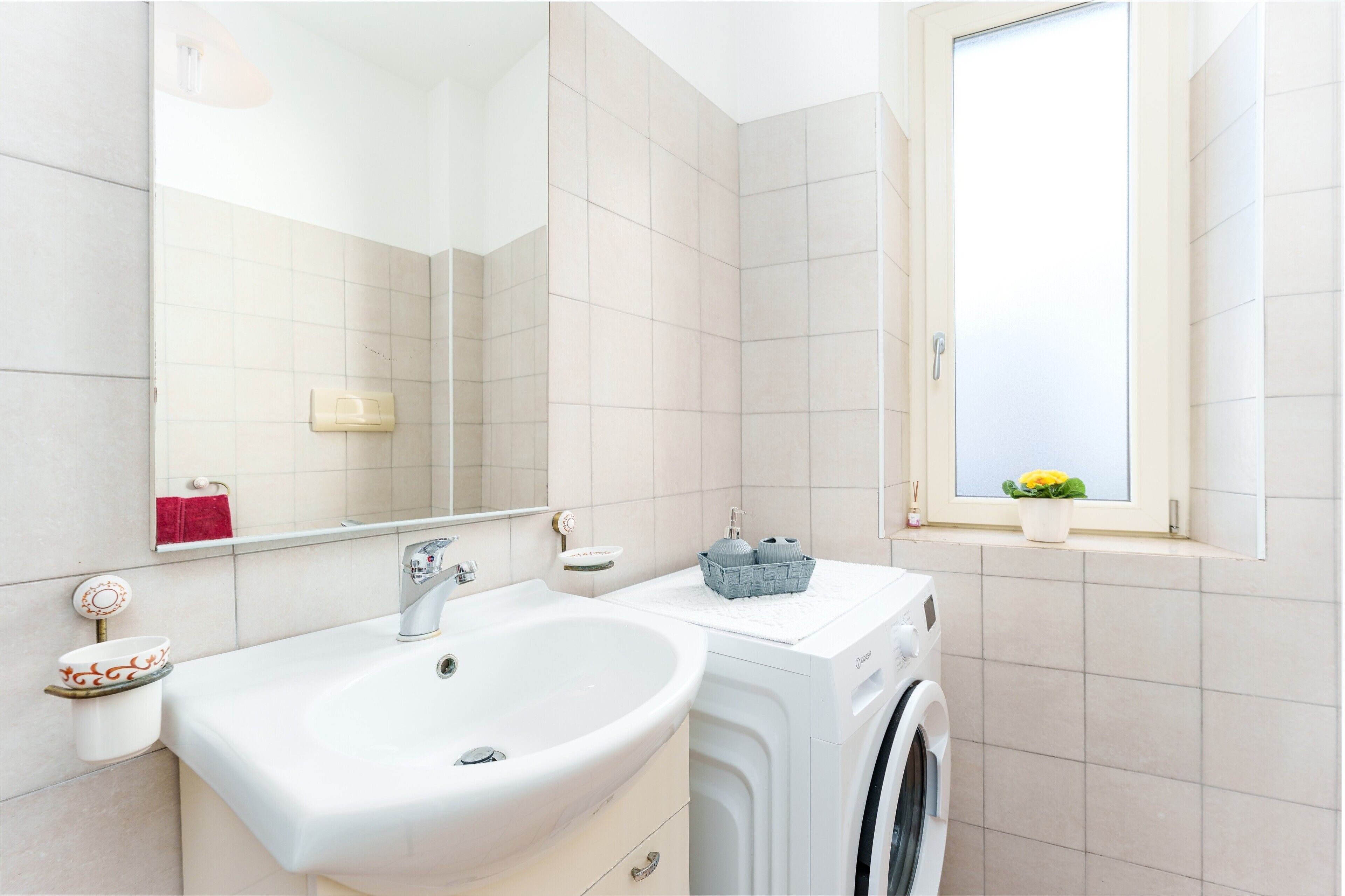Ein Badezimmer mit Waschbecken, Spiegel, Handtuchhalter und einem Fenster mit Blick.