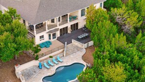 A two-story house with a swimming pool, outdoor seating, and a garden. - Grand Lakehouse Estate with Infinity Pool & Views (Austin)
