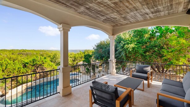 A covered outdoor area with a pool, seating, and a view of a lush landscape. - Grand Lakehouse Estate with Infinity Pool & Views (Austin)
