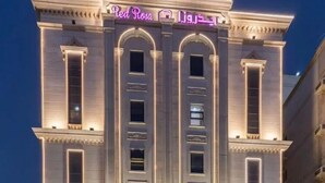 A building with a prominent arched entrance and a neon sign reading "Red Rosa." - Gardenia Park Al Rawabi Serviced Apartments Economy (Jeddah)