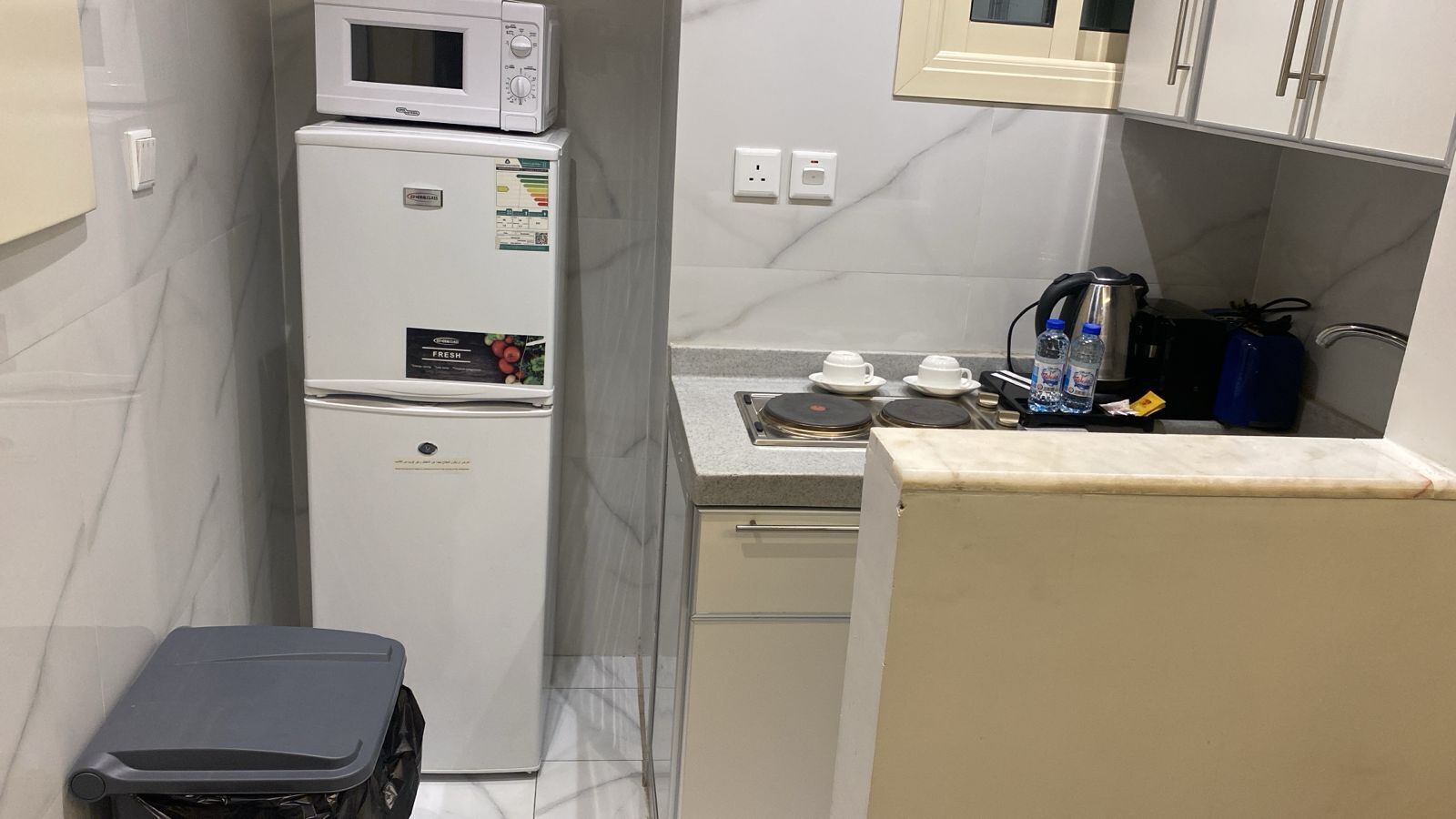 Una kitchenette compacta con refrigerador, microondas y estufa.