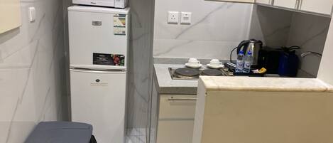 Una kitchenette compacta con refrigerador, microondas y estufa.